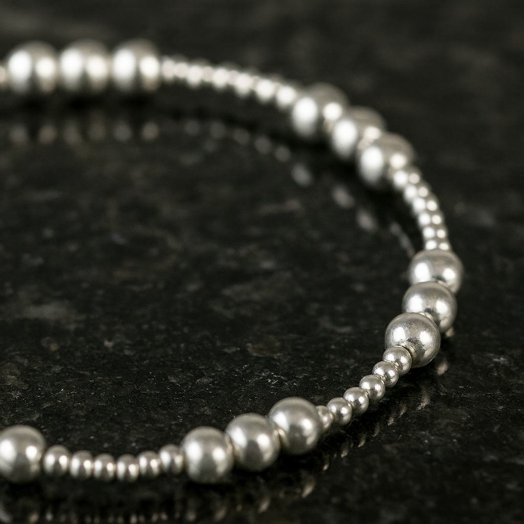 Silver beaded bracelet on a dark textured surface