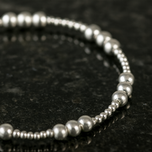 Silver beaded bracelet on a dark textured surface
