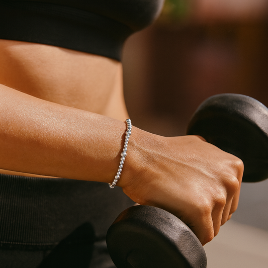 Person holding dumbbells with a bracelet on wrist, blurred background