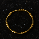 Gold beaded bracelet on a black textured background