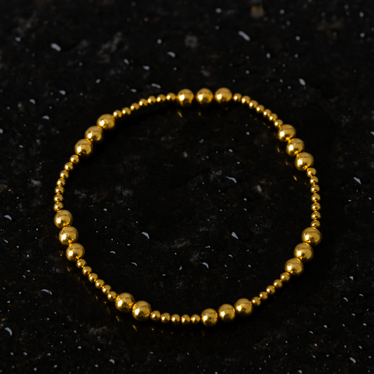 Gold beaded bracelet on a black textured background