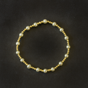 Bracelet with alternating gold and pearl beads on a black background
