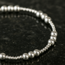 Silver beaded bracelet on a dark textured surface