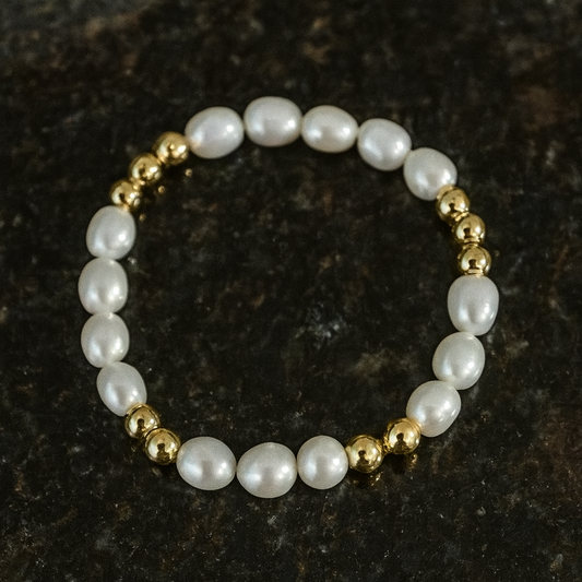 Pearl bracelet with gold beads on a dark textured background