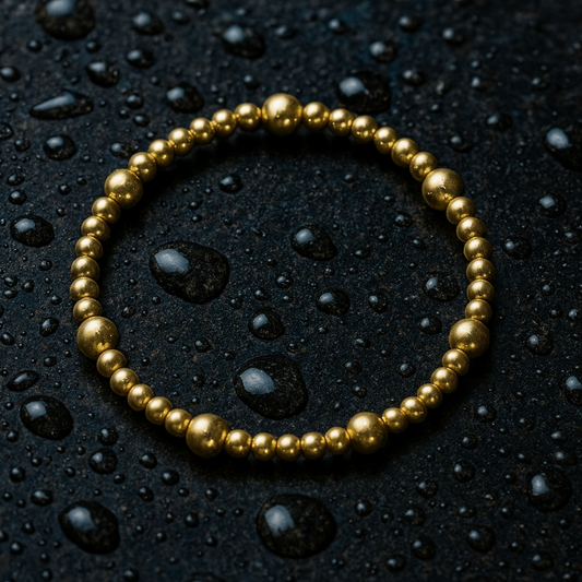 Gold bracelet on a black surface with water droplets