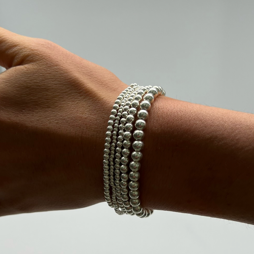 stack of silver ball bracelets on wrist